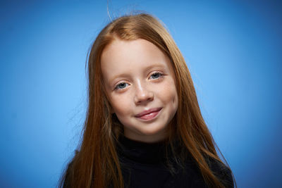 Close-up of young woman against blue background