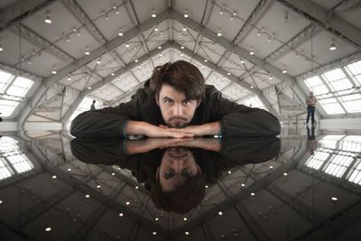 Portrait of young man standing against ceiling