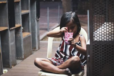 Full length of a girl drinking woman sitting outdoors