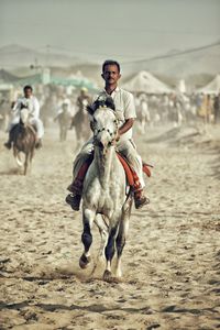 Full length of man riding horse on sand