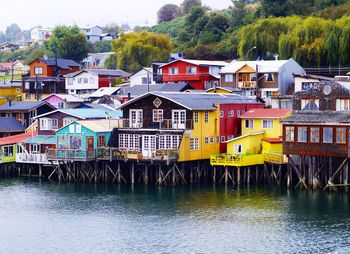 Houses by river against buildings