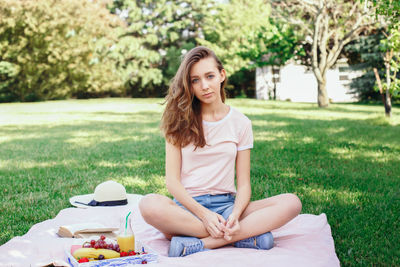 Portrait of young woman sitting on field