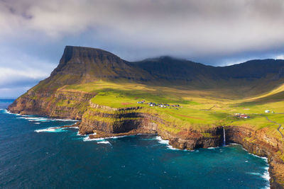 Scenic view of sea by mountains against sky