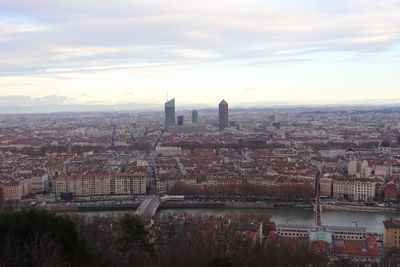 High angle view of city buildings against cloudy sky