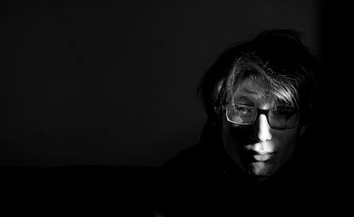 Portrait of man wearing eyeglasses in darkroom