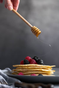 Pouring raw honey over homemade crepes on table, dark food photography