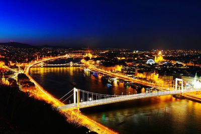 Illuminated bridge over river against sky at night