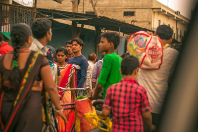 Rear view of people standing in front of built structure