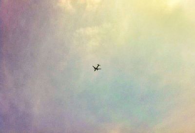 Low angle view of airplane flying against cloudy sky