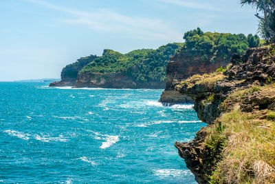 Scenic view of sea by cliff against sky