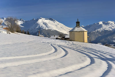 Snow covered buildings by mountain against sky