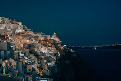 Aerial view of townscape by sea against blue sky