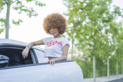 Woman with afro hair next to her white car