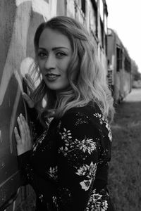 Portrait of young woman standing by train