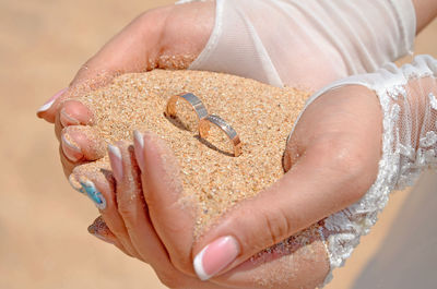 Close-up of woman holding hand on sand