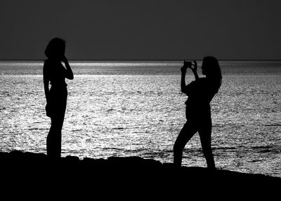 Silhouette woman standing on beach against sky