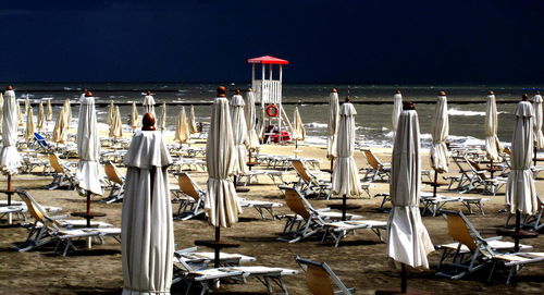 Closed canopies on beach against clear sky