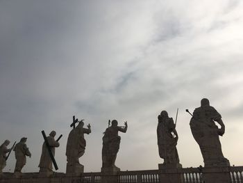 Low angle view of statues against cloudy sky