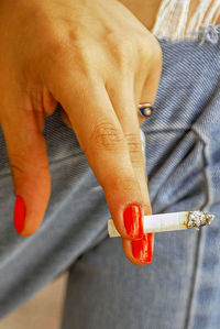 Midsection of man holding cigarette