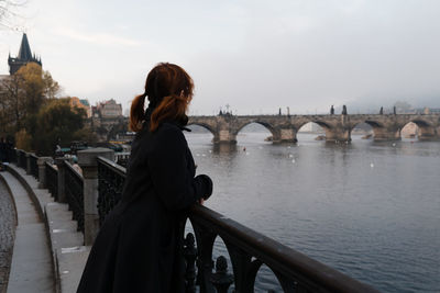 Side view of woman standing on bridge over river