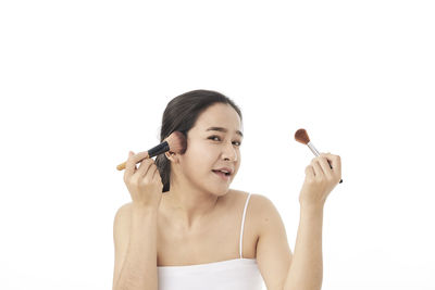 Portrait of young woman making face against white background