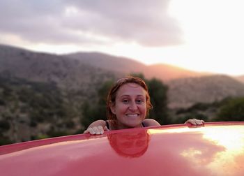 Portrait of smiling woman by car against mountains
