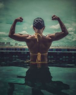 Rear view of shirtless man standing in swimming pool