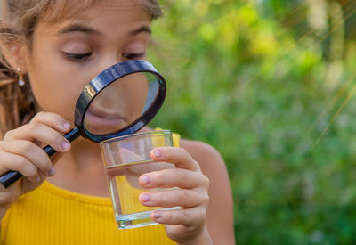 Girl looking at water through magnifying glass