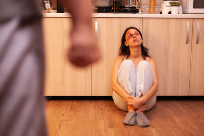 Portrait of young woman sitting on hardwood floor