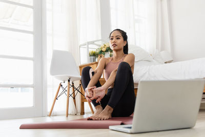 Young woman using phone while sitting at home