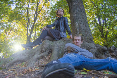 Portrait of friends sitting on tree in forest