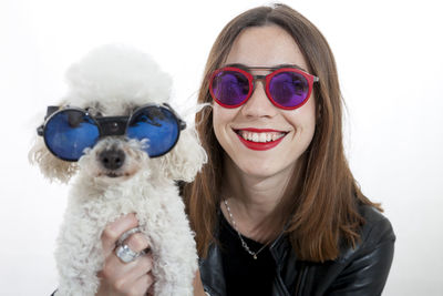 Portrait of little dog with sunglasses and her young mistress on white background