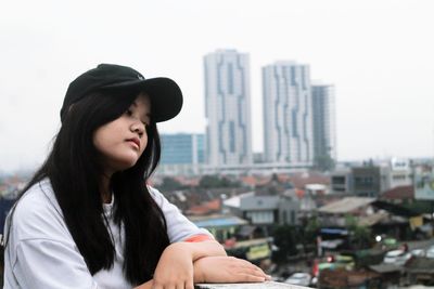 Portrait of young woman looking at city