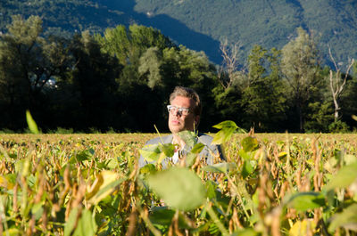 Mature man amidst plants on field