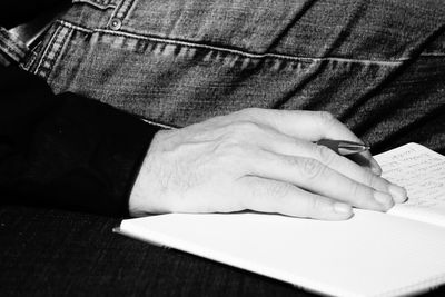 Midsection of man reading book on table
