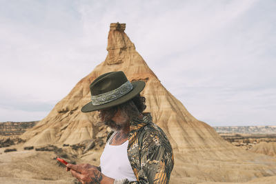 Young traveler using his cell phone. hipster man with hat using his cell phone in desert area