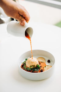 Hand of a waiter putting sauce in a freshly made dish in a restaurant