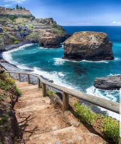 Scenic view of rocks by sea against sky
