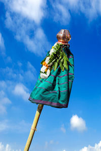 Low angle view of person against blue sky