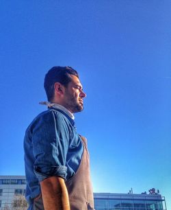 Low angle view of woman standing against clear blue sky