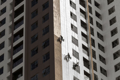 Low angle view of people painting residential building