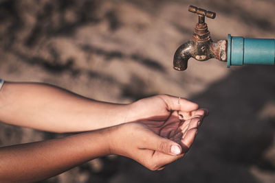 Close-up of hand holding faucet against blurred background