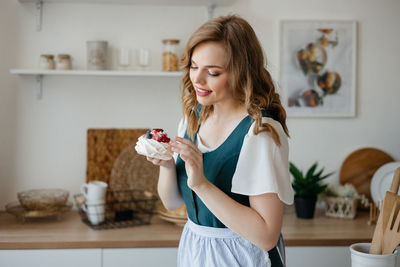Housewife holding a cake in her hands while standing in the kitchen