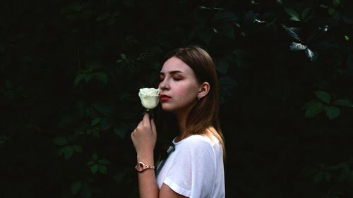 Side view of young woman holding rose