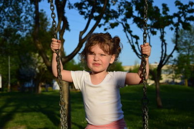 Cute girl looking away on swing at playground