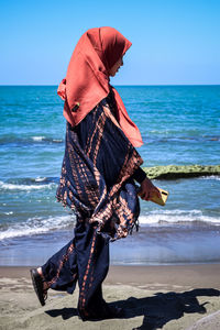 Woman with umbrella on beach against sky