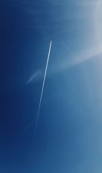 Low angle view of vapor trails against blue sky