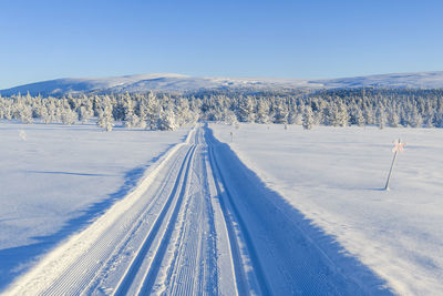 Snow covered landscape against blue sky