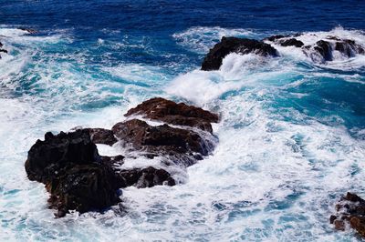 High angle view of waves splashing and crashing  on and over rocks white water surf 