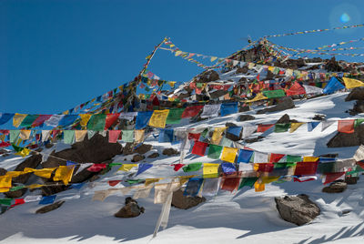 Low angle view of flags hanging against blue sky